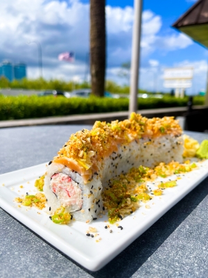 A straight-on shot of a lemon drop sushi roll on a plate.